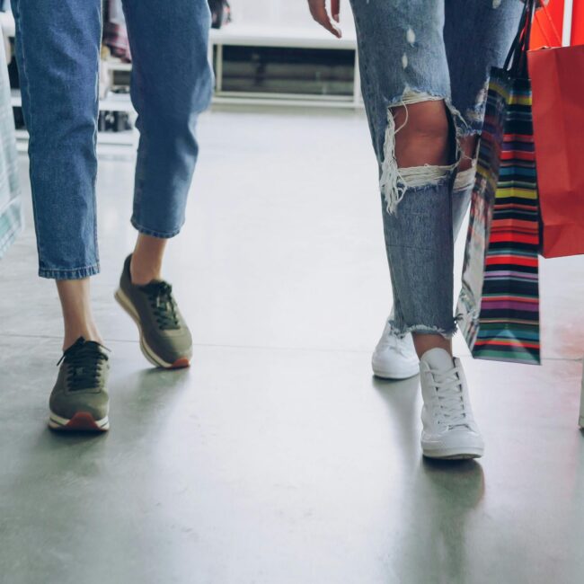 Women's legs walking through a store with shopping bags