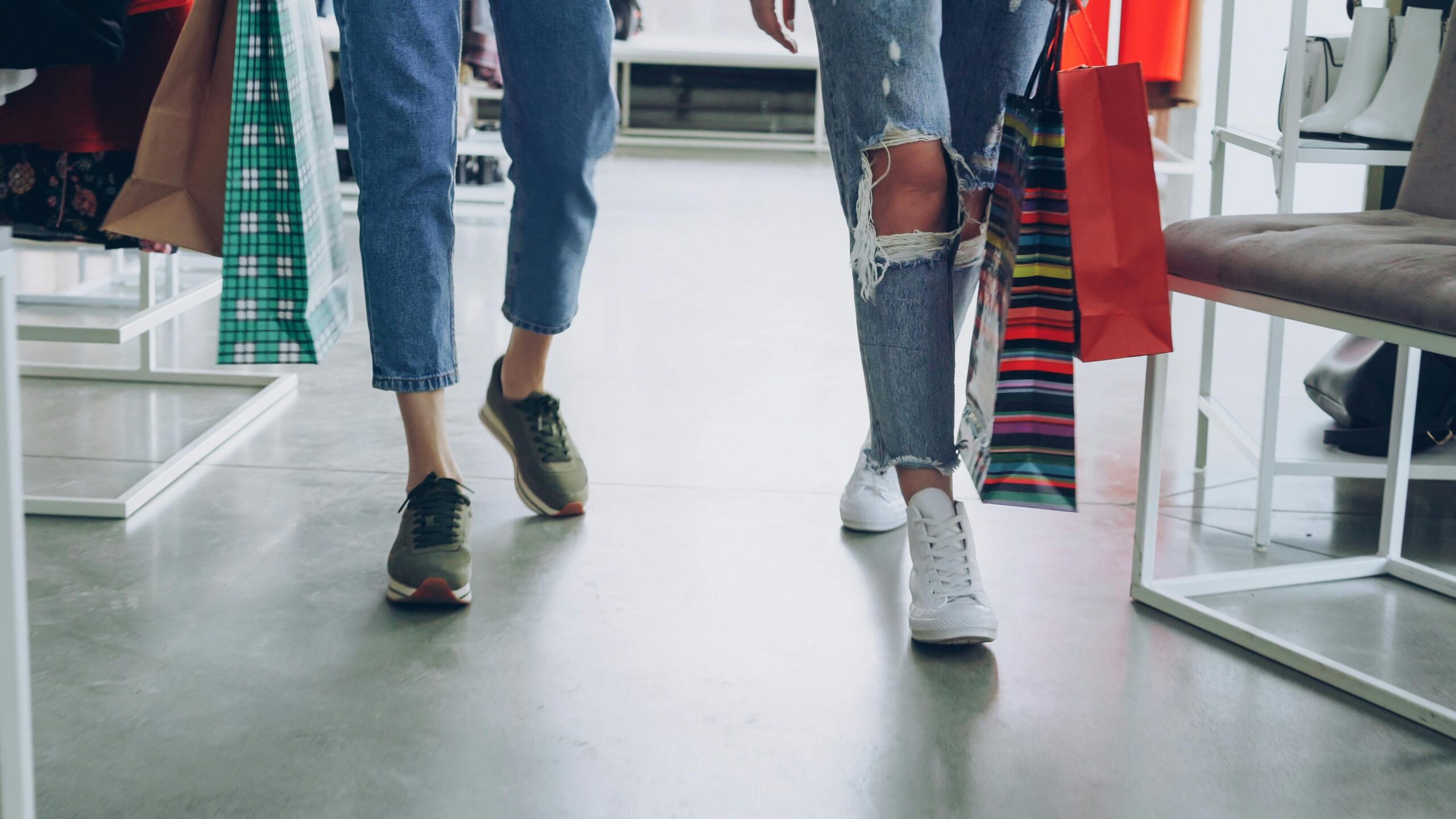 Women's legs walking through a store with shopping bags