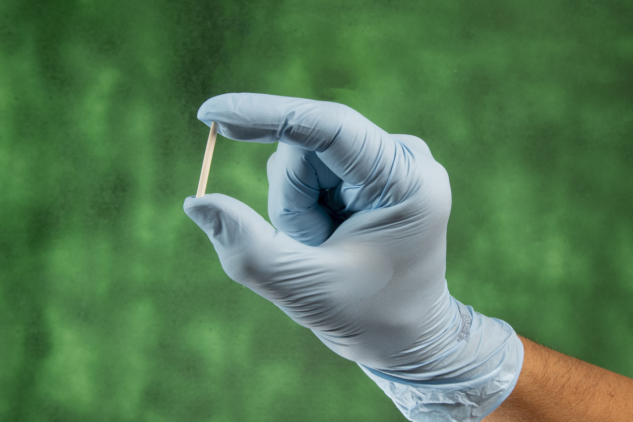 gloved hand holding contraceptive implant
